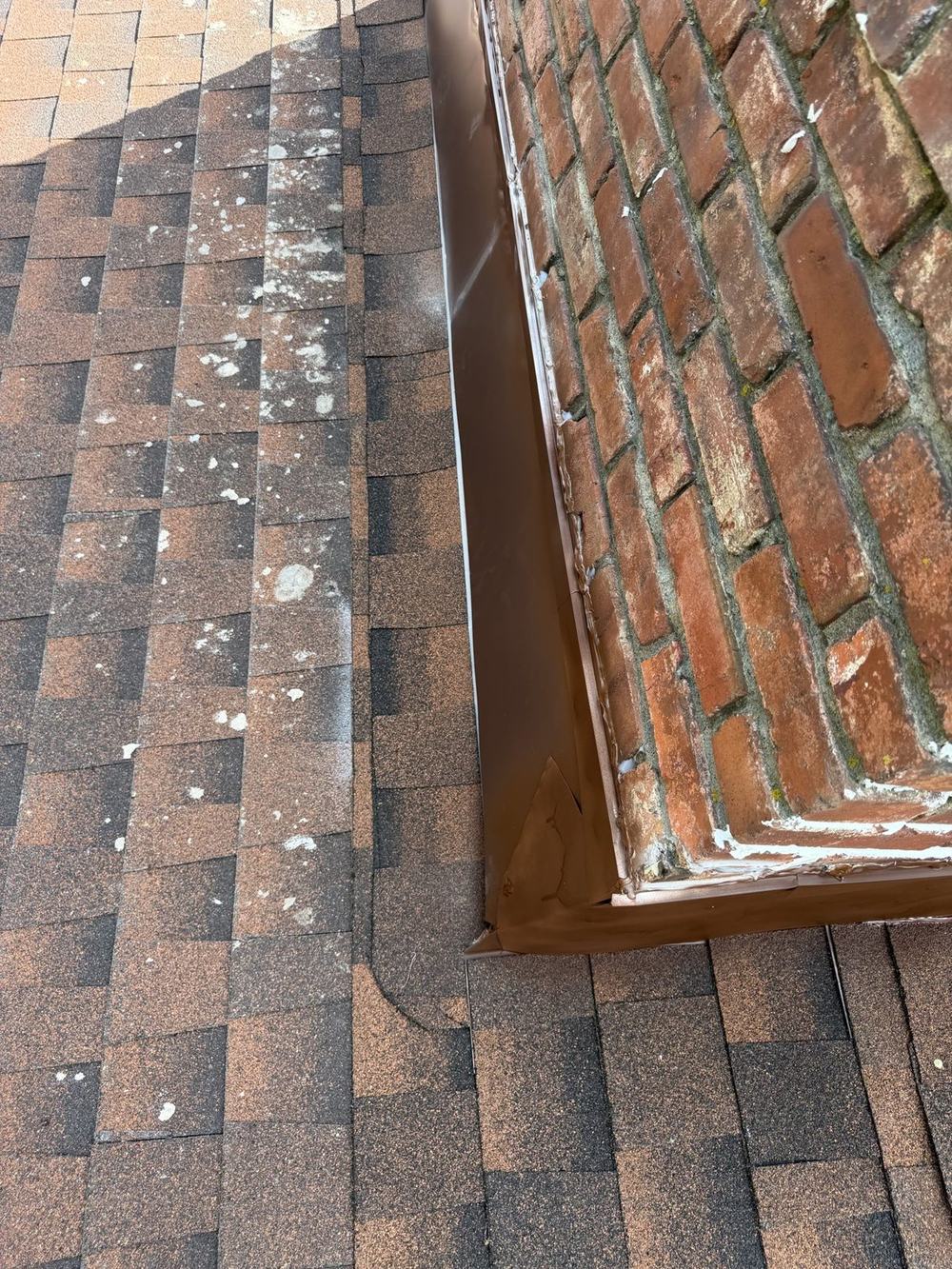 New metal counter-flashing installed around a brick chimney